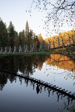 man in a yellow jacket crossing a suspension bridge in Finland