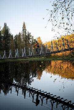 man in a yellow jacket crossing a suspension bridge in Finland