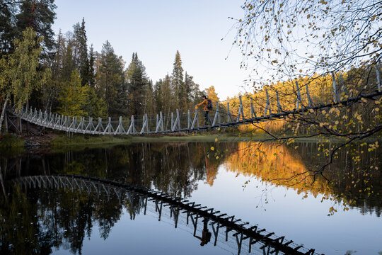 man in a yellow jacket crossing a suspension bridge in Finland