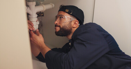 Plumber, man and pipe inspection in kitchen with safety for home maintenance or fixing leak by...