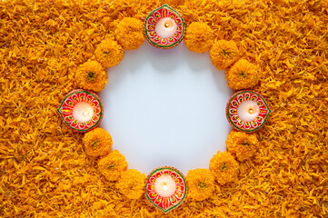 Decorative orange color marigold flowers and petals rangoli with clay diya lamp for Diwali festival on white space background.