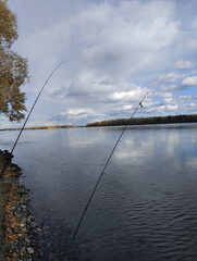 Two fishing rods against the background of the river in the evening. Autumn fishing.