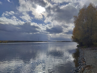 Autumn beautiful horizontal evening landscape with a full-flowing Siberian river, clouds, strong...