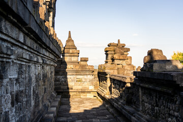 Warm afternoon light from sunset hits carved Buddha statue, Stupa and stone wall relief at the ancient historical Buddhist UNESCO site of Borobudur (Barabudur), Magelang, Indonesia.