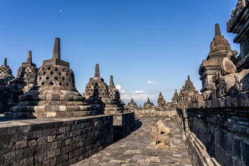 Many Stupas on top of Borobudur Temple - an important historical Buddhist monument in Magelang, Indonesia. Moon visible in sky.