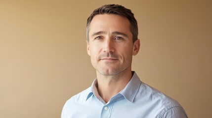 Confident middle-aged man with short brown hair wearing a light blue shirt against a neutral backdrop