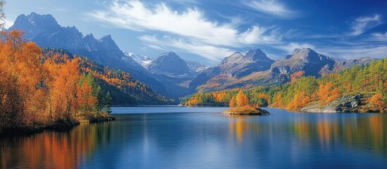 Obraz premium Tranquil lake surrounded by fall foliage and majestic mountain peaks under a clear sky with wispy clouds.