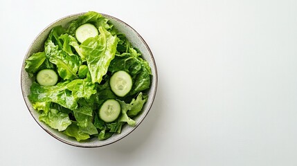 Obraz premium A simple green salad bowl featuring romaine lettuce, cucumbers, and a lemon vinaigrette, set against a clean white background for a fresh vibe.