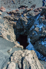 Hole of an inactive fumarole in lava rock at Monti Sartorius Mount Etna with snow during winter time, Catania, Sicily, Italy