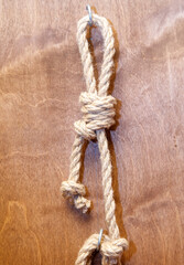 A rope is tied to a hook on a wooden surface
