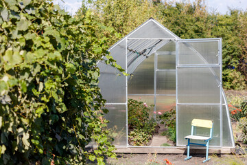 A greenhouse with a yellow chair sitting in front of it