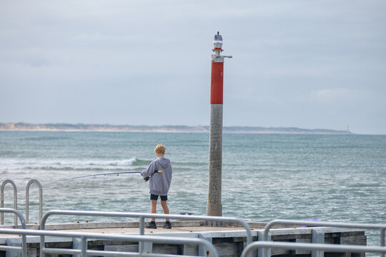 Boy fishing near a marker post at the end of the pier Barwon Heads