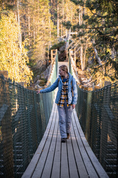 woman in a blue jacket crossing a suspension bridge in Finland