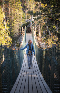 woman in a blue jacket crossing a suspension bridge in Finland