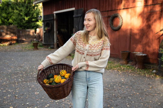 Woman holding decorative pumpkins in wicker basket