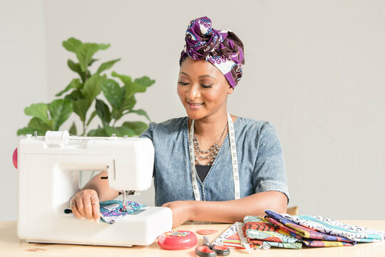 Woman using a sowing machine to make headwraps
