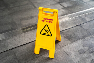 Yellow Caution slippery wet floor sign on the wet ground. Copy space.