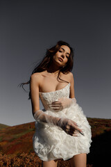 An Elegant Model Poses in a Stunning White Dress Against a Dramatic Dark Landscape