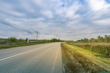 A road with a few trees in the background and a few birds flying in the sky