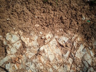 The dredged soil reveals rocks that are visible in the sun. Red and yellow rocks where the soil is dug. Cut soils - sandstone, stone, clay, structures and sand layers. 