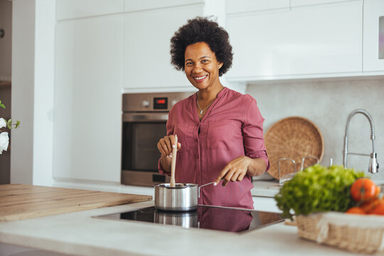 Woman Smiling While Cooking in a Modern Kitchen Environment