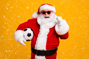 Portrait of his he nice attractive cheerful cheery Santa holding in hands ball celebrating having fun win winner luck attainment isolated over bright vivid shine vibrant yellow color background