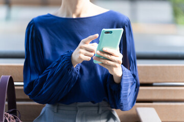 屋外でスマートフォンを操作している若い女性