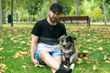 A young man with his dog in a park on a sunny day.