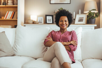 Relaxed Woman Smiling While Sitting on a Comfortable Sofa at Home