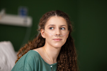 Recovering from a recent flu, a girl with an oxygen tube gazes through the hospital window, finding...