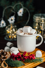 Christmas drink hot chocolate with marshmallows at festive illuminated decoration. Selective focus