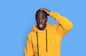Surprised man in yellow hoodie touching his head
