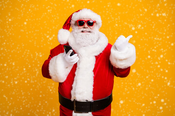 Portrait of his he nice attractive cheerful fat overweight bearded Santa using device showing copy space like follow subscribe isolated bright vivid shine vibrant yellow color background