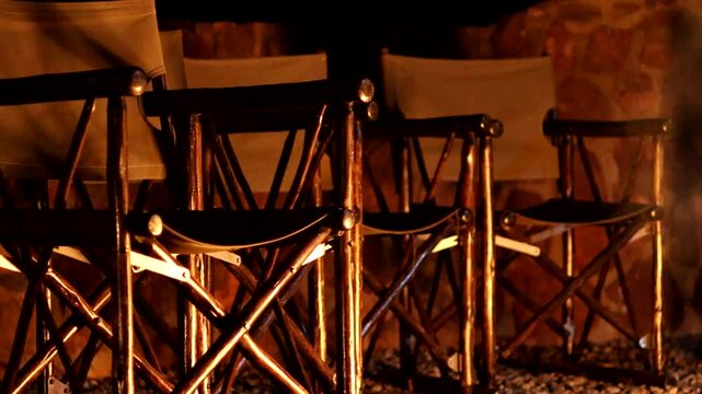 Directors Chairs reflect the warm flickering campfire light at night, peaceful and rustic ambiance - no people