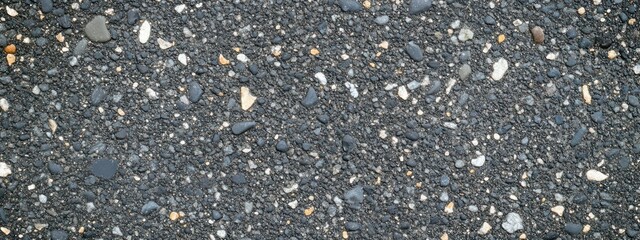 Close-up view of various small stones and gravel on a dark surface.