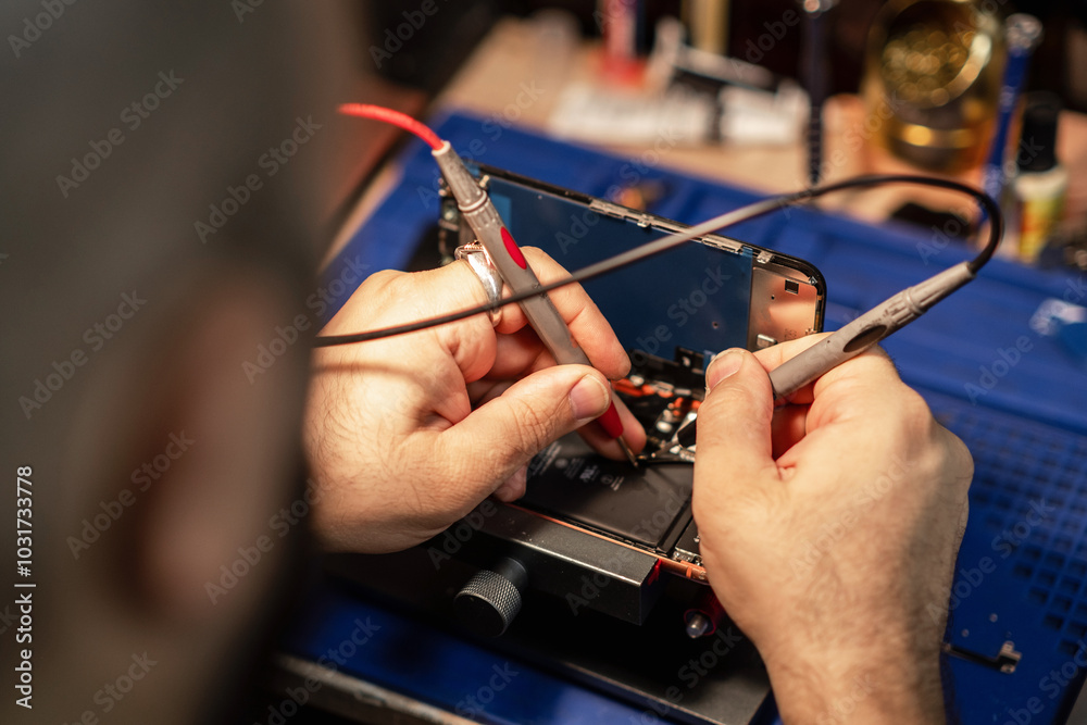 Poster technician performing smartphone battery repair in a workshop using precision tools and equipment du