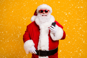 Portrait of his he nice attractive cheerful cheery Santa using device gadget chatting web service shopping order isolated over bright vivid shine vibrant yellow color background