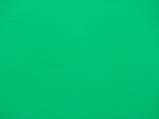 Fototapeta premium Green background. The cement walls are painted green. Green rough wall as texture and background.The surface of plastered wall is uneven and has rough marks. Green color texture pattern. Rough surface