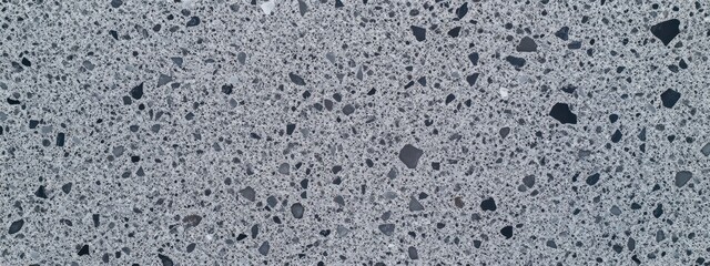 Obraz premium Close-up of a textured concrete surface with small aggregate stones.