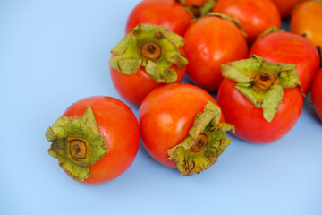 Ripe persimmon fruits on blue background.	
