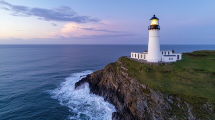 Obraz premium A picturesque lighthouse stands majestically on a rocky cliff, overlooking turbulent ocean waves under a stunning twilight sky.