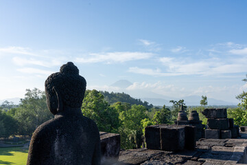 Buddha statue on top of Borobudur Temple - an important historical Buddhist monument in Magelang, Indonesia. Mount Sumbing visible in background.