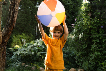 Small child playing with beach ball outdoors. Summer lawn games.