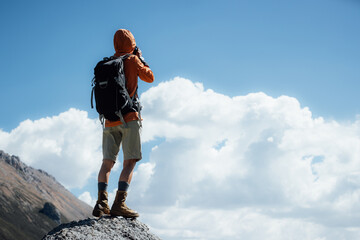 Woman photographer taking picture on high altitude mountain top,with a lake in the distance