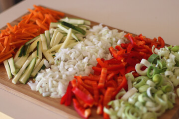 Chopped leek, red pepper, onion, zucchini and carrot on the chopping board. Cooking and meal prepping at home. Selective focus.