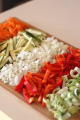 Chopped leek, red pepper, onion, zucchini and carrot on the chopping board. Cooking and meal prepping at home. Selective focus.