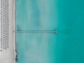 Aerial drone view of wooden pier and turquoise waters at Playa de Muro, Alcudia, Mallorca