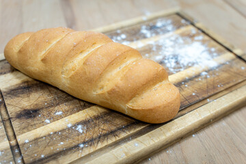 A loaf of white bread on a wooden board.