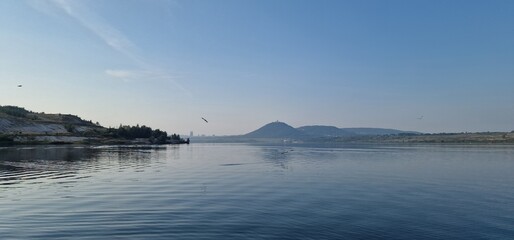 sea gulls above lake Most under the peak Hněvín with castle and lookout, artificial post mining revitalised coal mine small power plant aroun