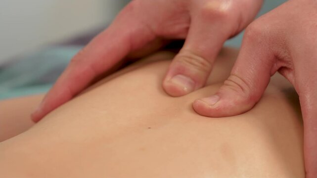 Close up of hands child masseur doing restorative back massage in hospital. Professional man masseur doing massage on back of boy in close up. Childhood scoliosis